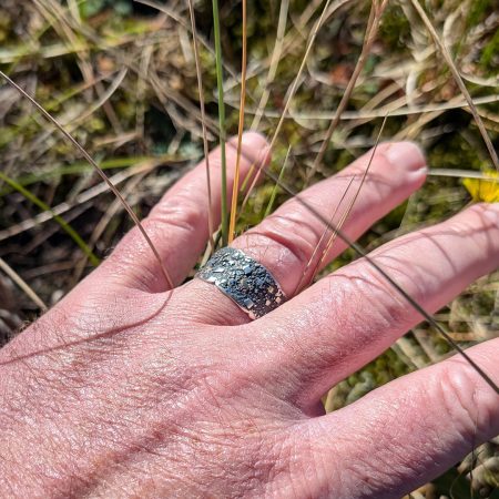 Textured sterling silver wide band ring with18k gold accents worn to show scale