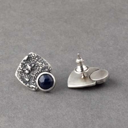 Backs of blue sapphire stud earrings in textured sterling silver