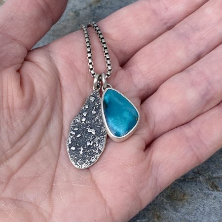 American turquoise pendant duo held in hand to show scale