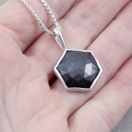 Mink brown sapphire pendant in brushed sterling silver held in hand to show scale