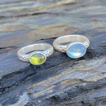 Seafoam rings with aquamarine and peridot laid on the rocks