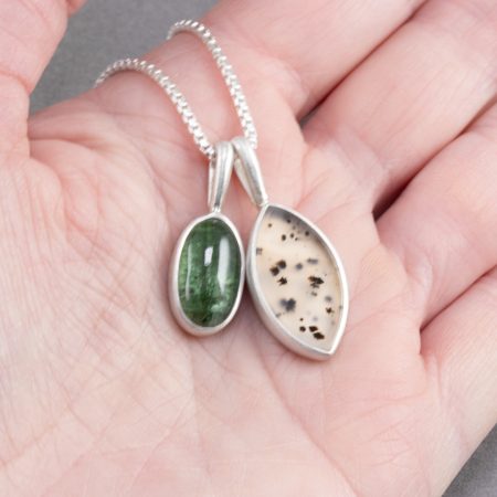 Green tourmaline and dendritic agate duo pendants held in hand to show scale