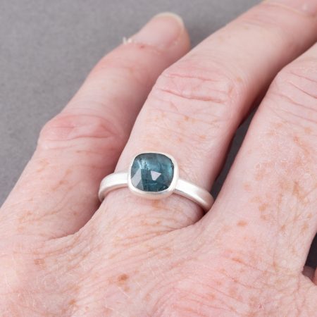 Teal blue tourmaline ring in brushed sterling silver worn on hand to show scale