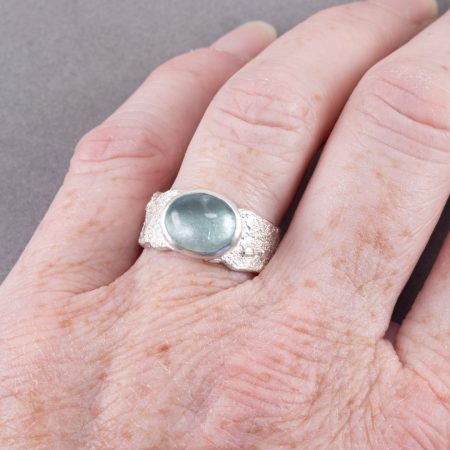 Blue tourmaline ring in textured sterling silver, worn on hand to show scale
