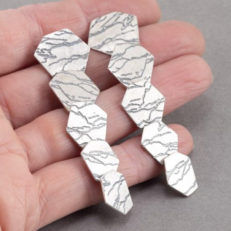 Long rag slate earrings held in hand to show scale