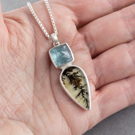 Dendritic agate and blue tourmaline pendant in sterling silver held in hand to show scale