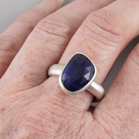 Rose cut iolite ring in brushed sterling silver worn on hand to show scale.