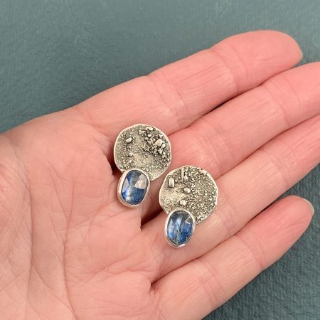 Kyanite stud earrings held in hand to show scale